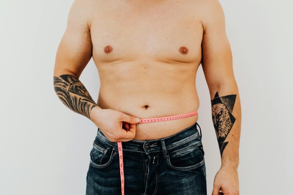 Man measuring his waist with tape, focused on fitness and weight management.